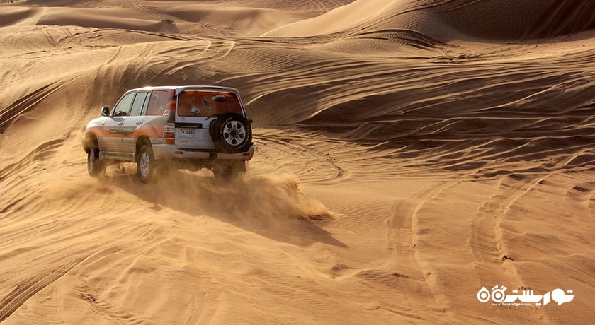 سرگرمی سواری با خودروی شاستی بلند در تپه های شنی شهر امارات متحده عربی کشور ابوظبی
